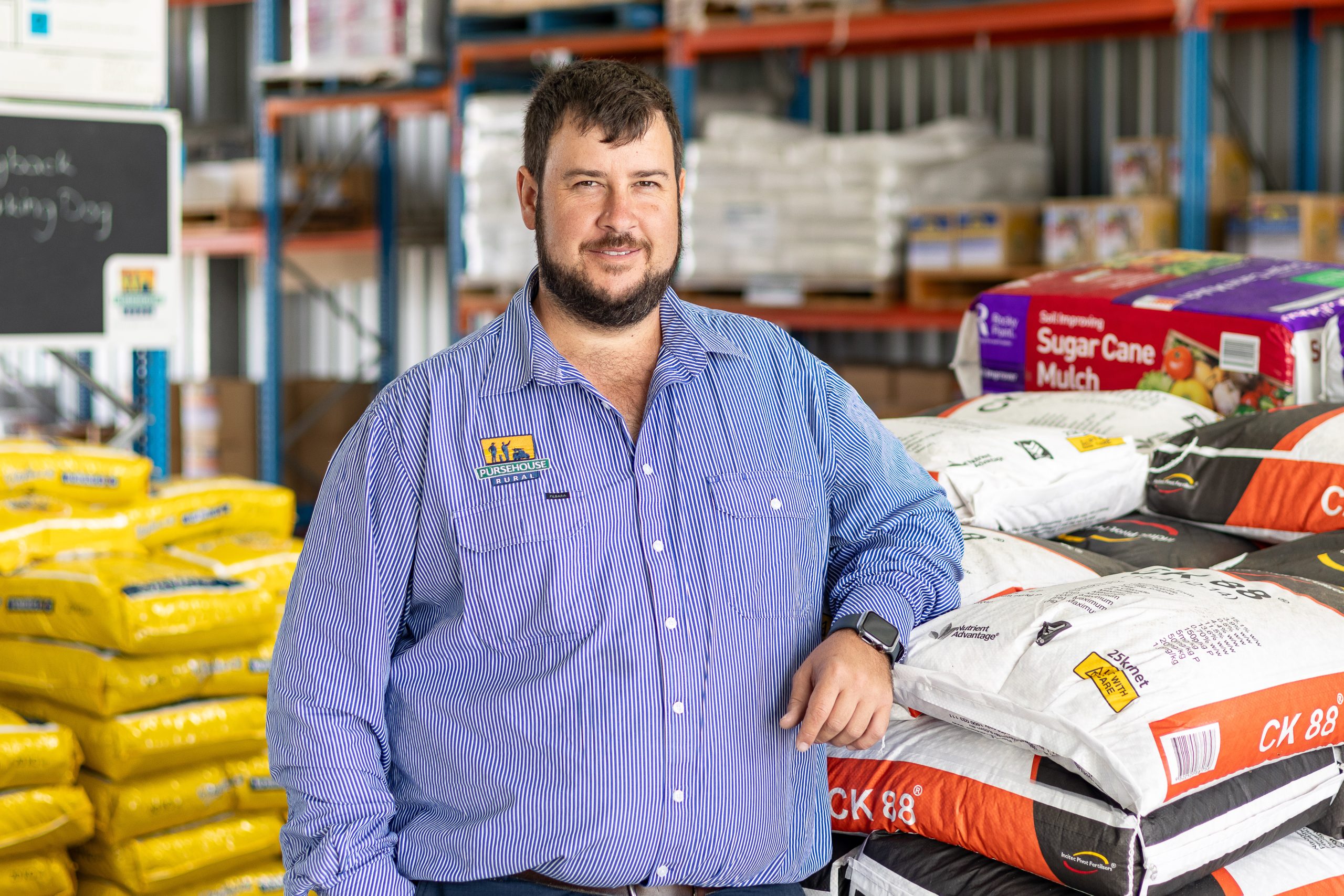 Male Pursehouse Rural employee stands by rural merchandise in store