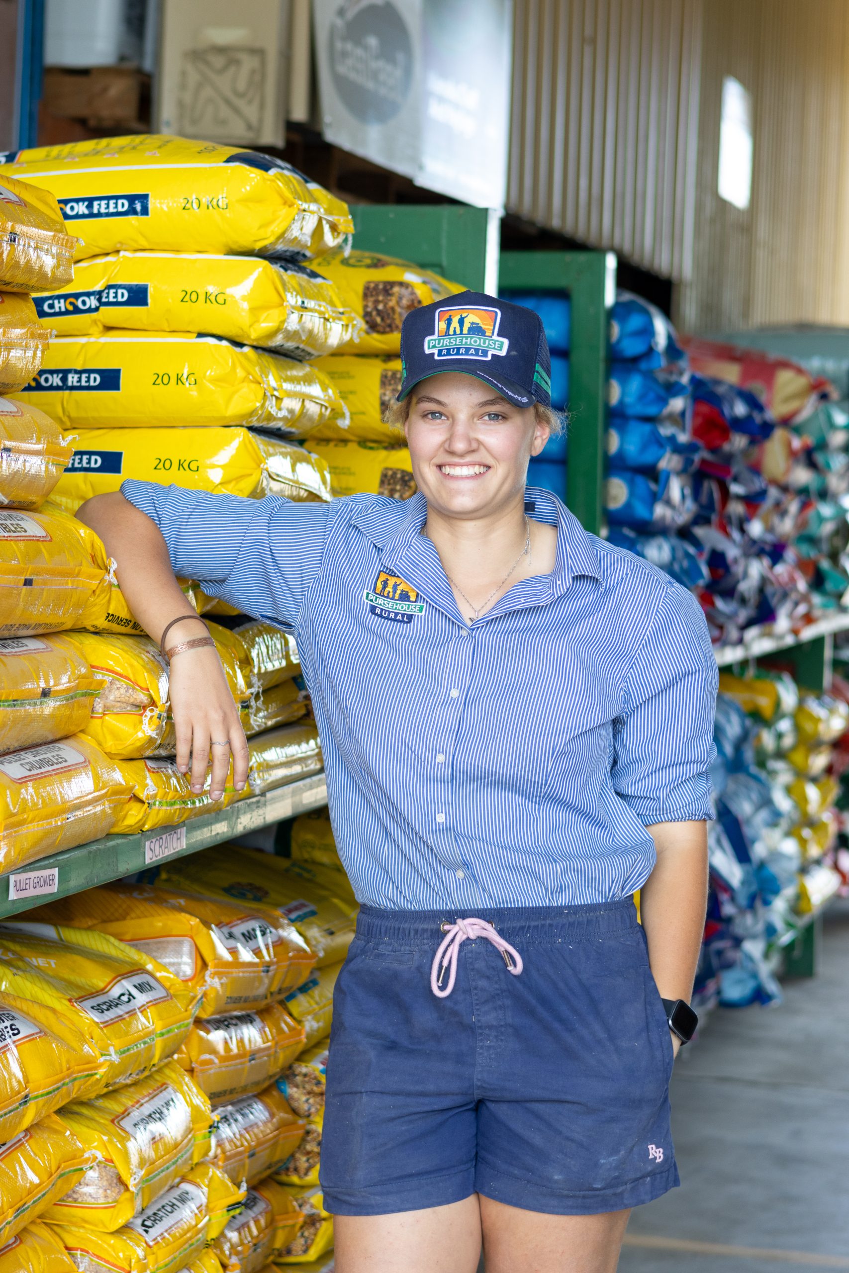 Female Pursehouse Rural employee standing by merchandise in branch driveway